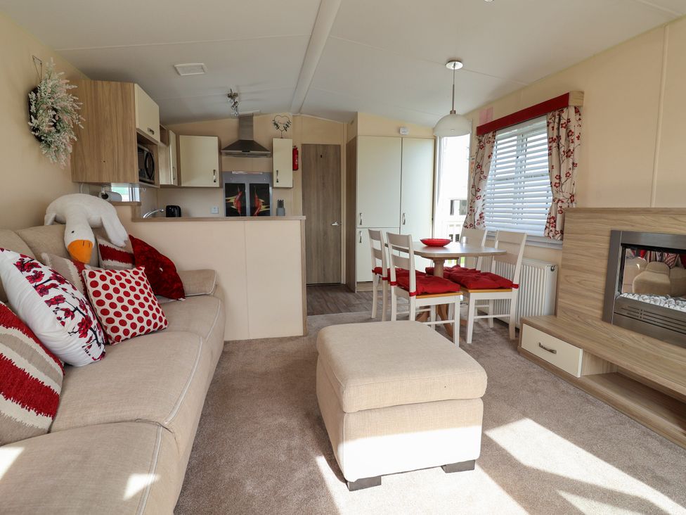 A living room with a sofa and dining area at 15 Elm Crescent in Rhyl