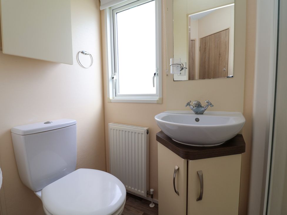 A bathroom with a toilet, sink, and mirror at 15 Elm Crescent in Rhyl