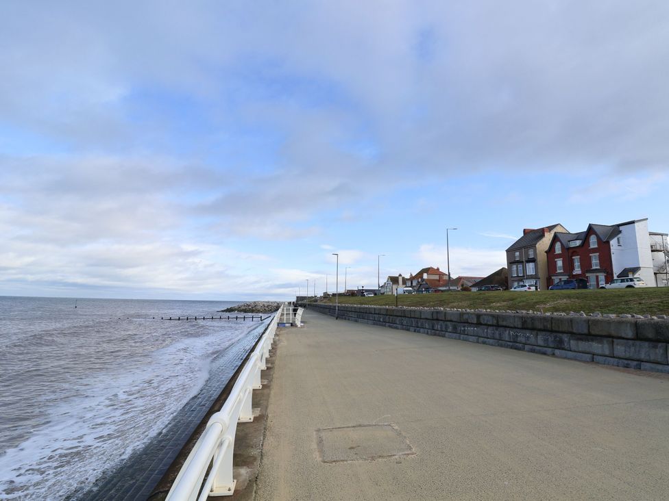 A pathway along the sea with buildings and clouds at Tidal Retreat in Rhyl