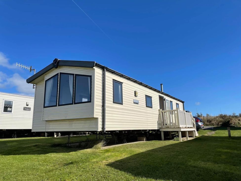 A caravan with a wooden deck at Blue Dolphin Holiday Home in Gristhorpe