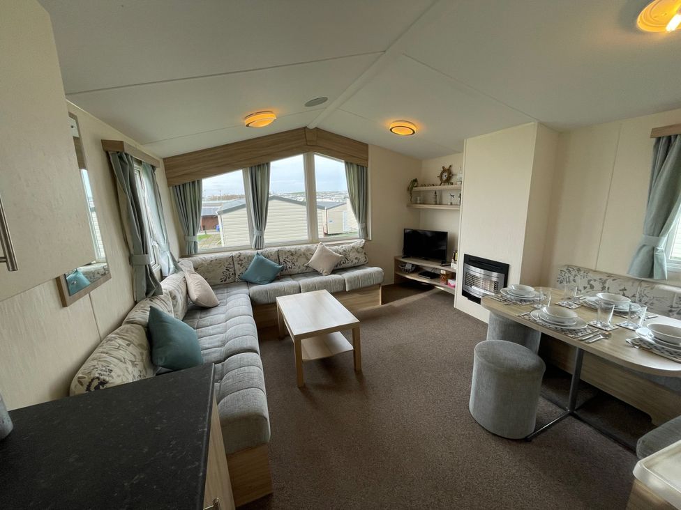 A living room with a sofa and dining table at Blue Dolphin Holiday Home in Gristhorpe
