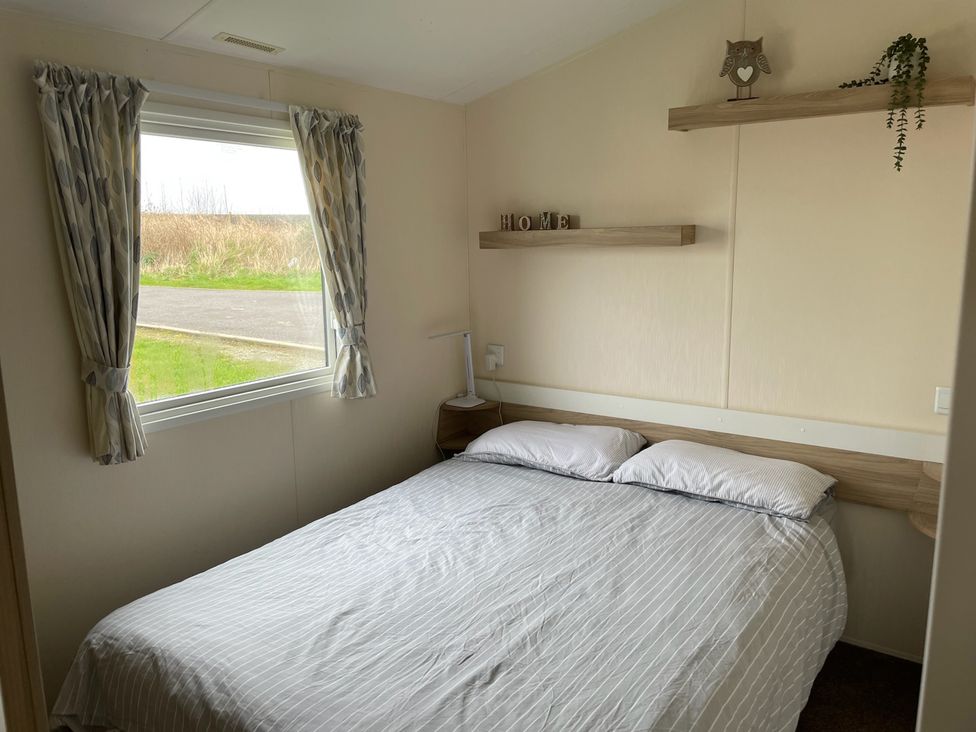 A bedroom with a bed and a window at Blue Dolphin Holiday Home in Gristhorpe