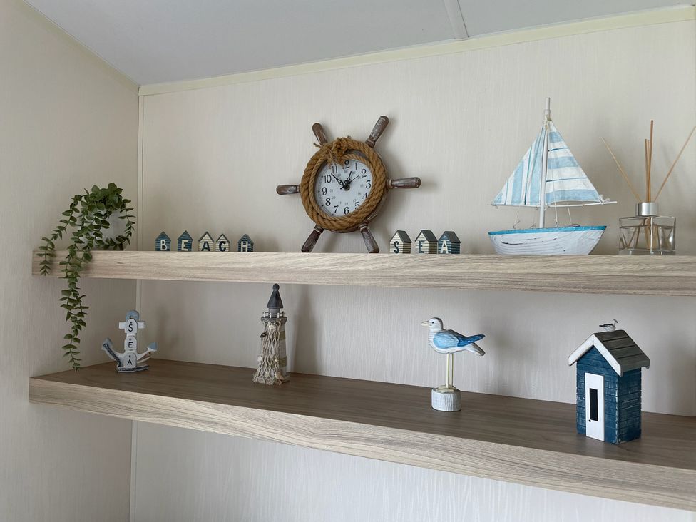 A shelf with decorative items including a clock and a sailboat at Blue Dolphin Holiday Home in Gristhorpe