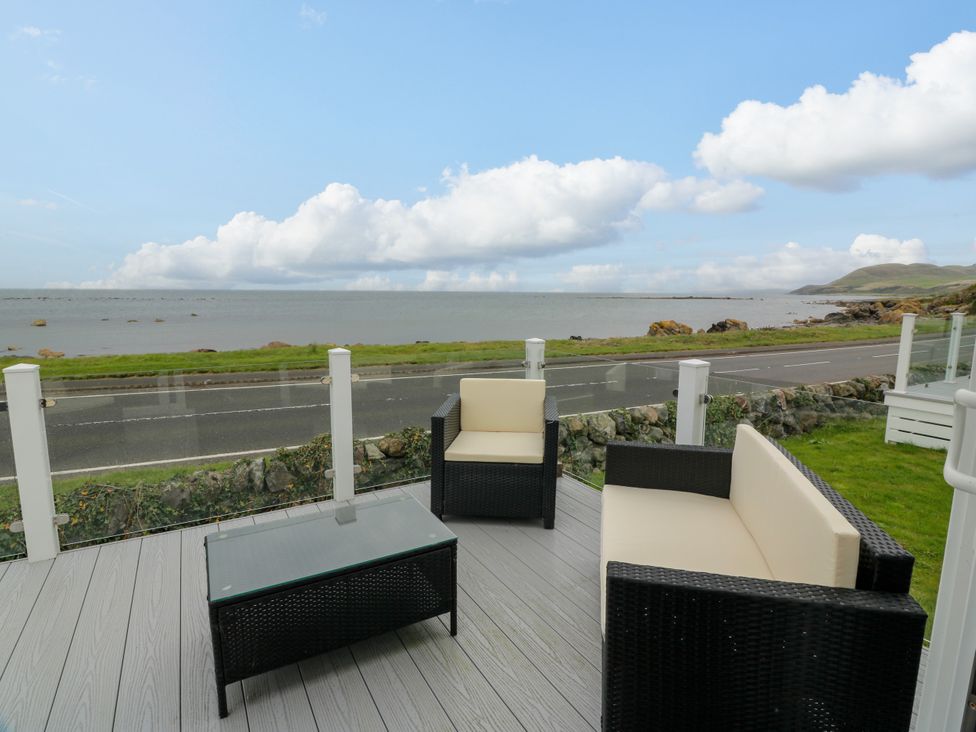 A patio area with seating overlooking the sea at Caravan in Girvan