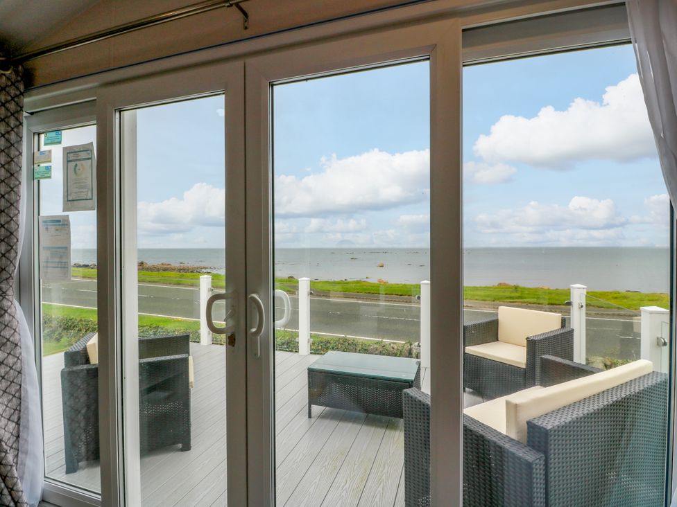 A living room with sliding glass doors and a view of the sea at Caravan in Girvan