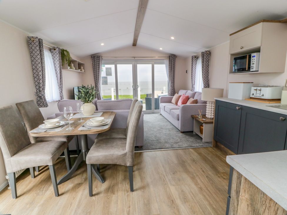 A living room with a dining area and kitchen appliances at Caravan in Girvan