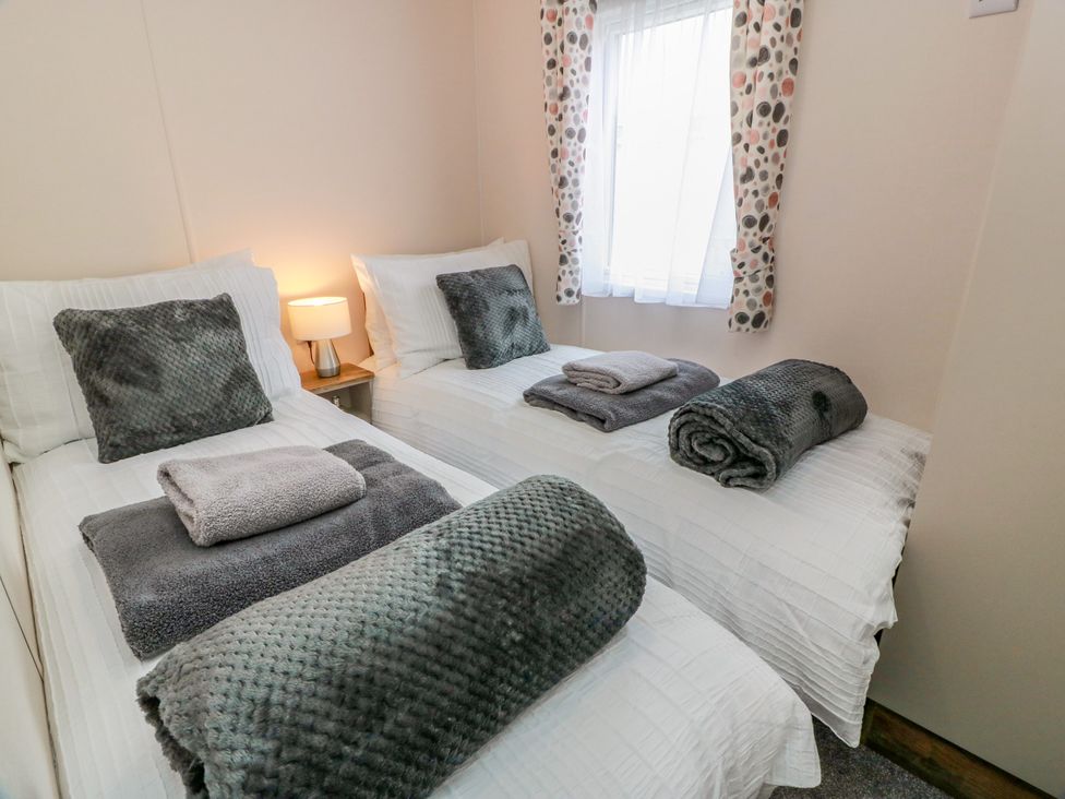 A bedroom with two beds and a lamp at Caravan in Girvan