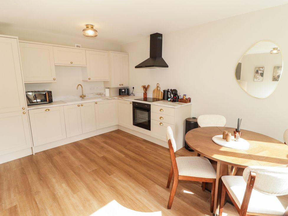 A kitchen with cabinets and dining table at Flat 4 in Tenby