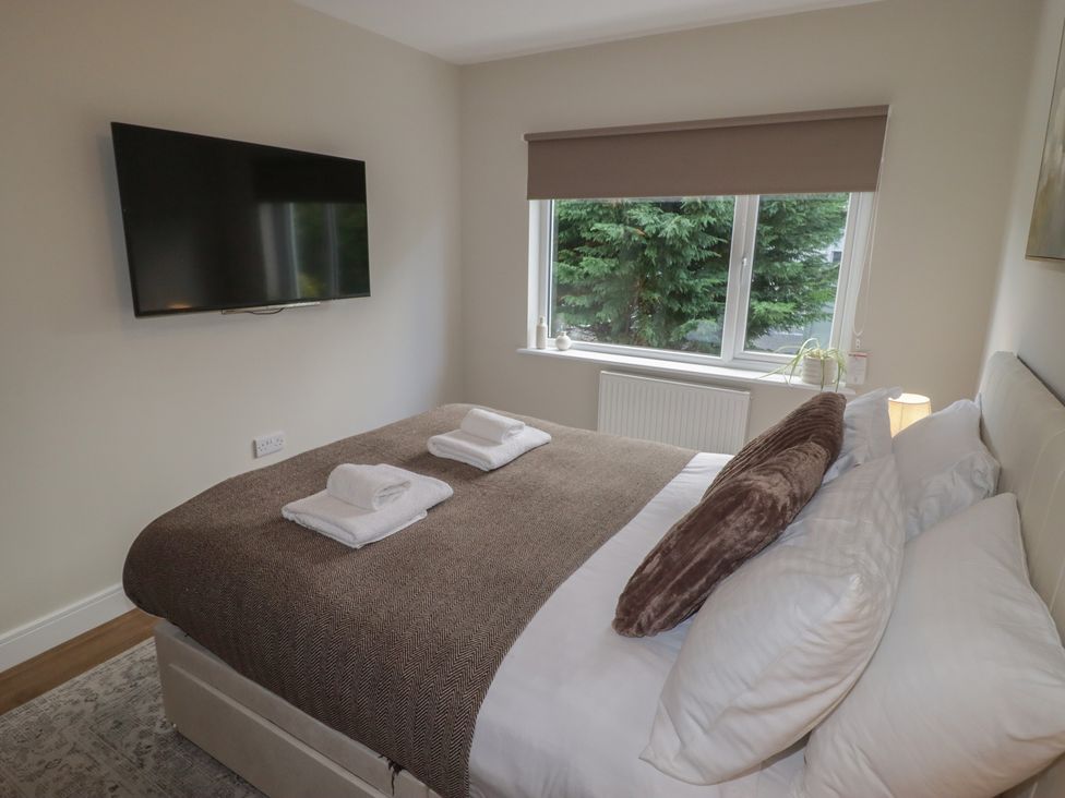 A bedroom with a television and view outside at Flat 4 in Tenby