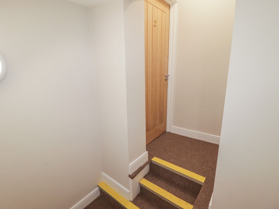 A corridor with stairs and a door at Flat 4 Tenby