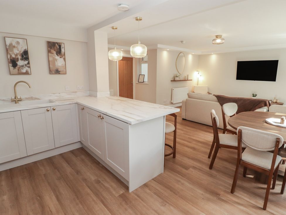 A kitchen and dining area with cabinets and furniture at Flat 1 in Tenby