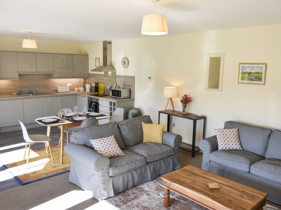 A living room with a sofa, coffee table, and kitchen area at The Hayloft in Hexham