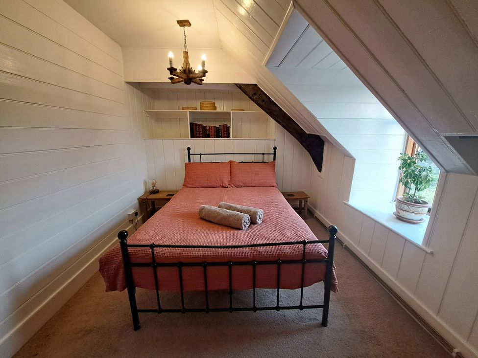 A bedroom with a bed, shelves, and a window at Y Cwtch in Dolgellau