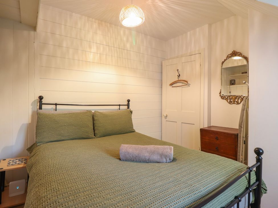 A bedroom with a bed and a mirror at Y Cwtch in Dolgellau
