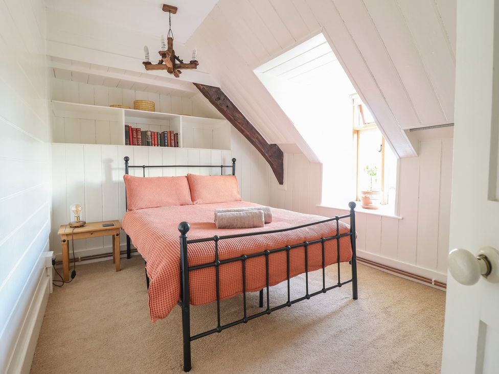 A bedroom with a bed and books on a shelf at Y Cwtch in Dolgellau