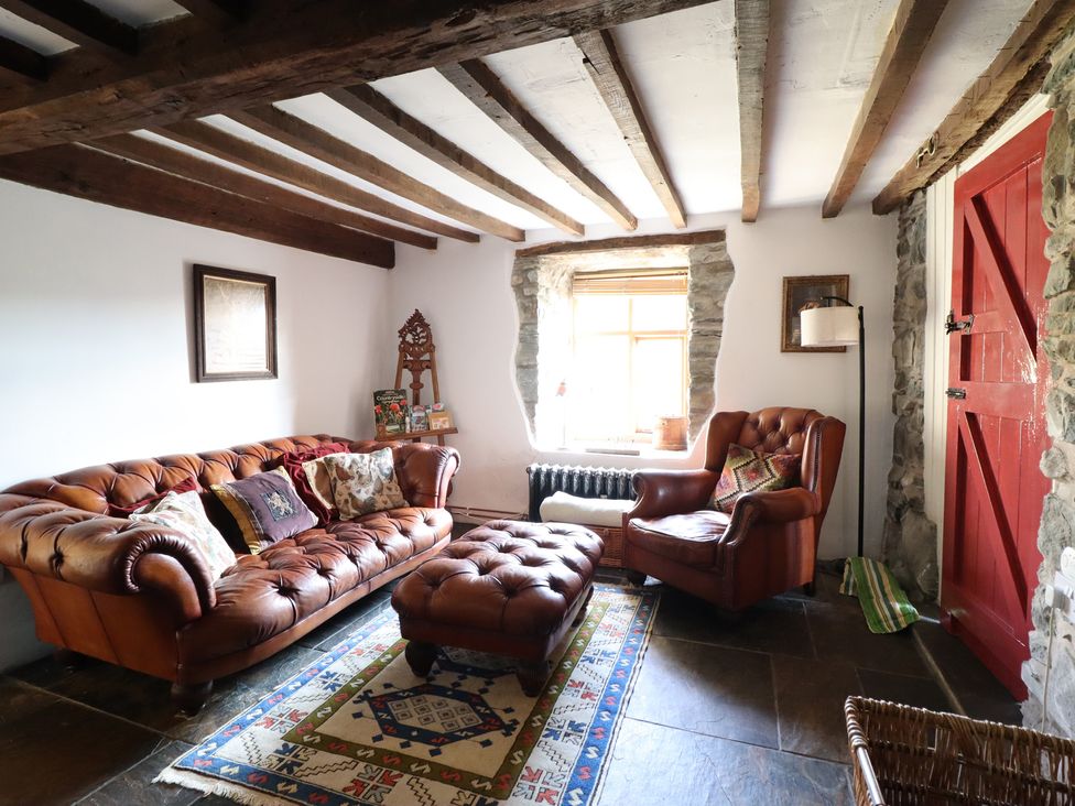 A living room with a leather sofa and an ottoman at Waen Fechan in Dolgellau
