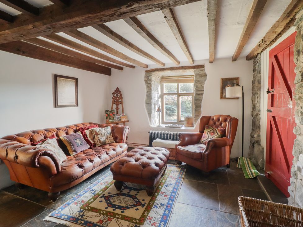 A sitting room with a leather sofa and ottoman at Waen Fechan in Dolgellau