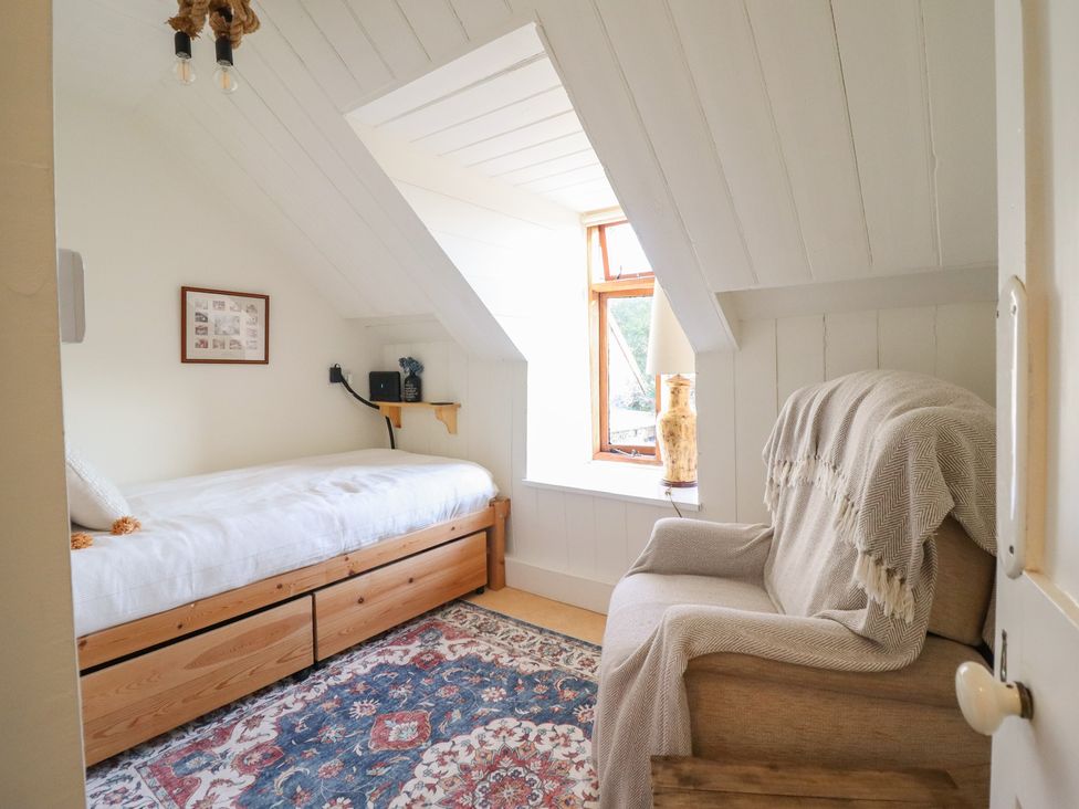 A bedroom with a bed, armchair and window at Waen Fechan in Dolgellau