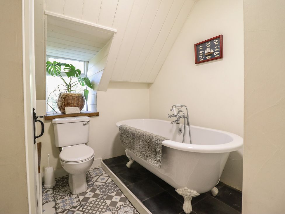 A bathroom with a bathtub, toilet, and a window at Waen Fechan in Dolgellau