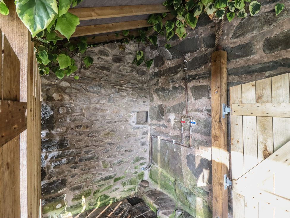 An outdoor shower area with stone walls and a wooden door at Waen Fechan in Dolgellau