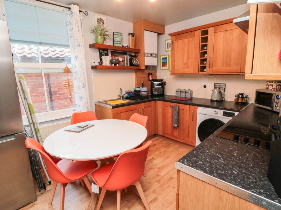 A kitchen with a round table and red chairs at 1 St. Anns Lane in Whitby