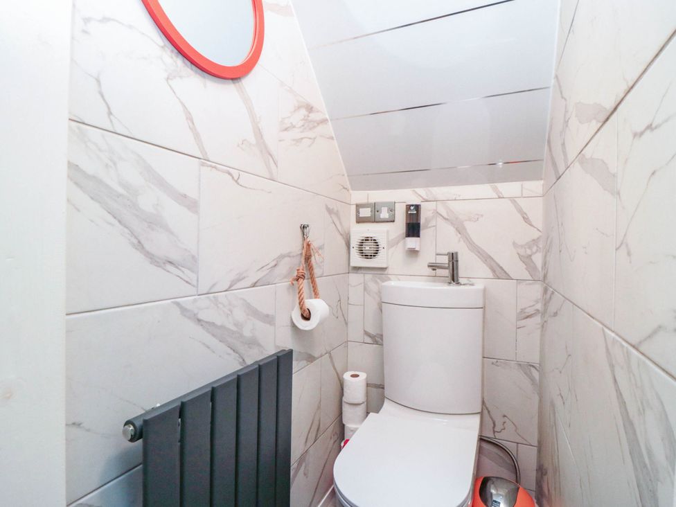 A bathroom with a toilet and mirror at 1 St. Anns Lane in Whitby