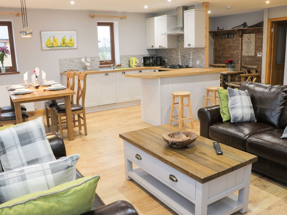 A living room with a dining area and kitchen at Woodman's Lodge in Nantwich
