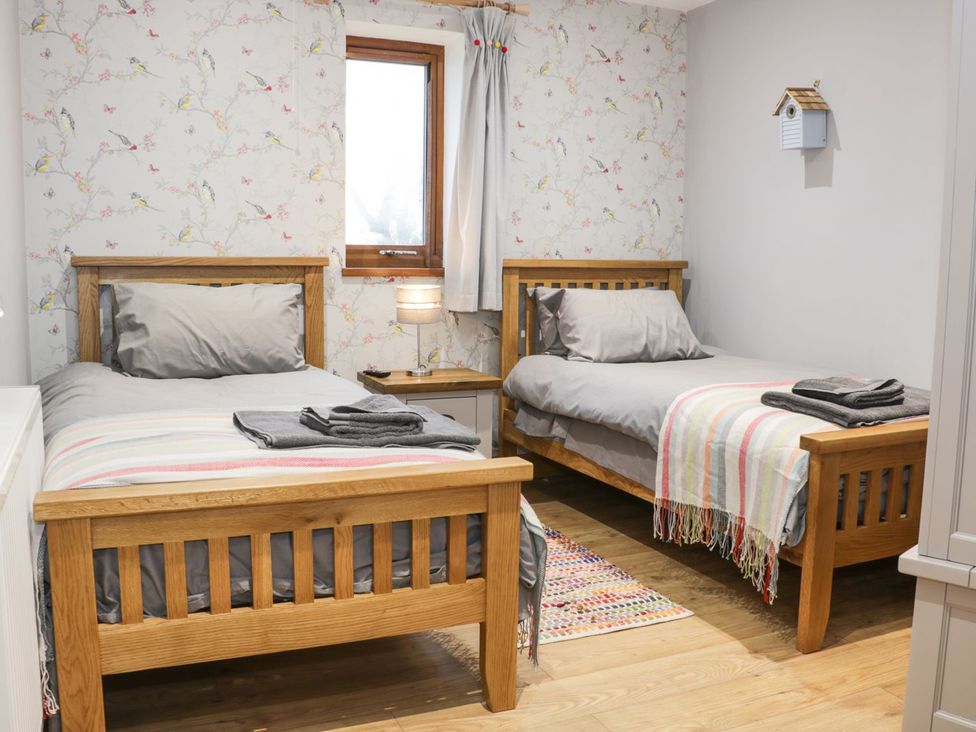 A bedroom with two single beds and a bedside table at Woodman's Lodge in Nantwich