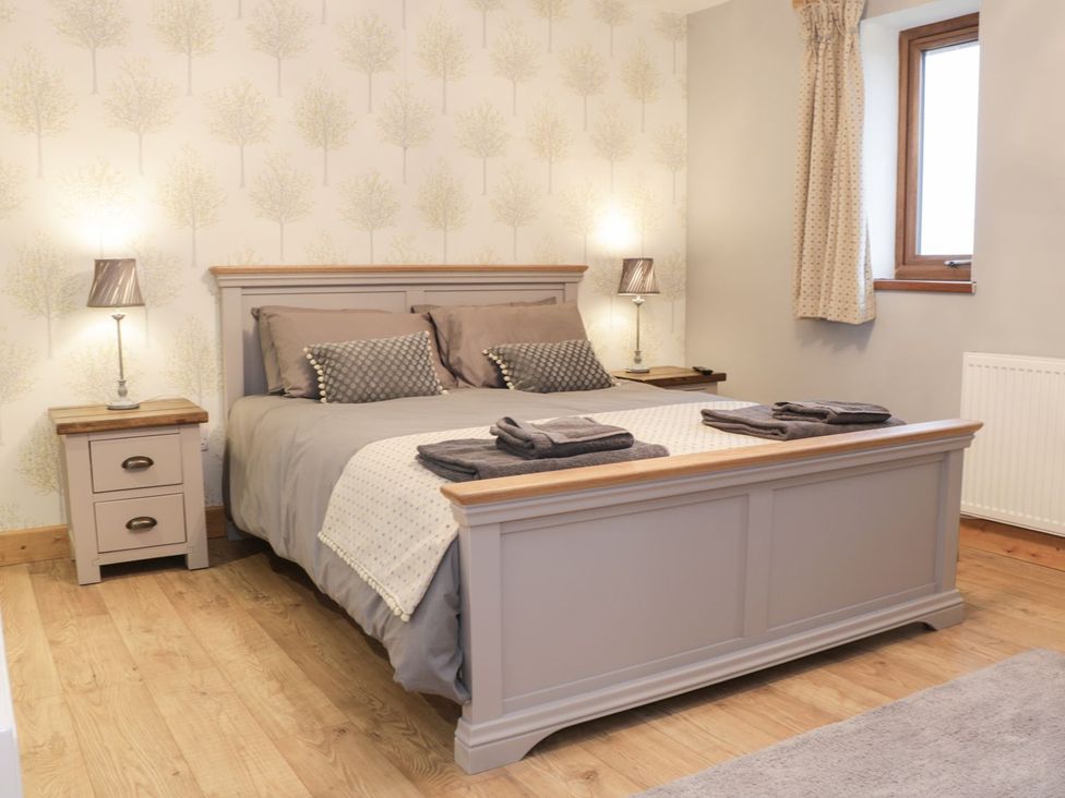 A bedroom with a bed and nightstands at Woodman's Lodge in Nantwich