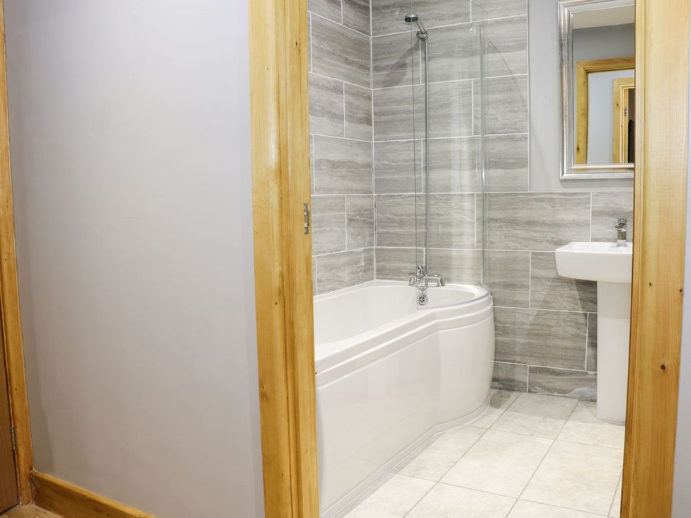 A bathroom with a bathtub and sink at Woodman's Lodge in Nantwich