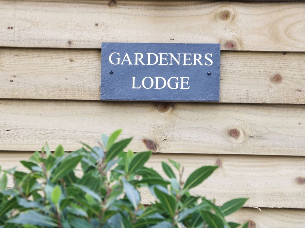 A sign reading Gardener's Lodge mounted on a wooden wall at Gardener's Lodge in Nantwich