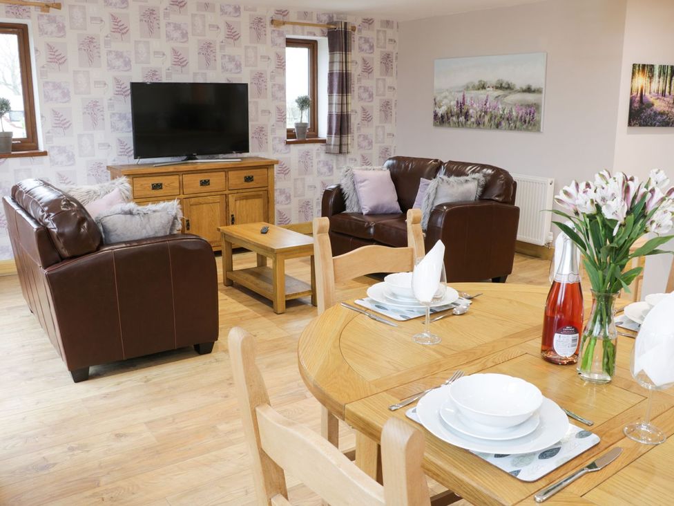 A living room with a television and dining table at Gardener's Lodge in Nantwich