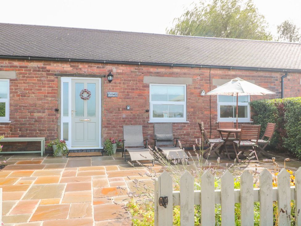 An outdoor area with a table and chairs in front of a door at The Byre in Ashbourne