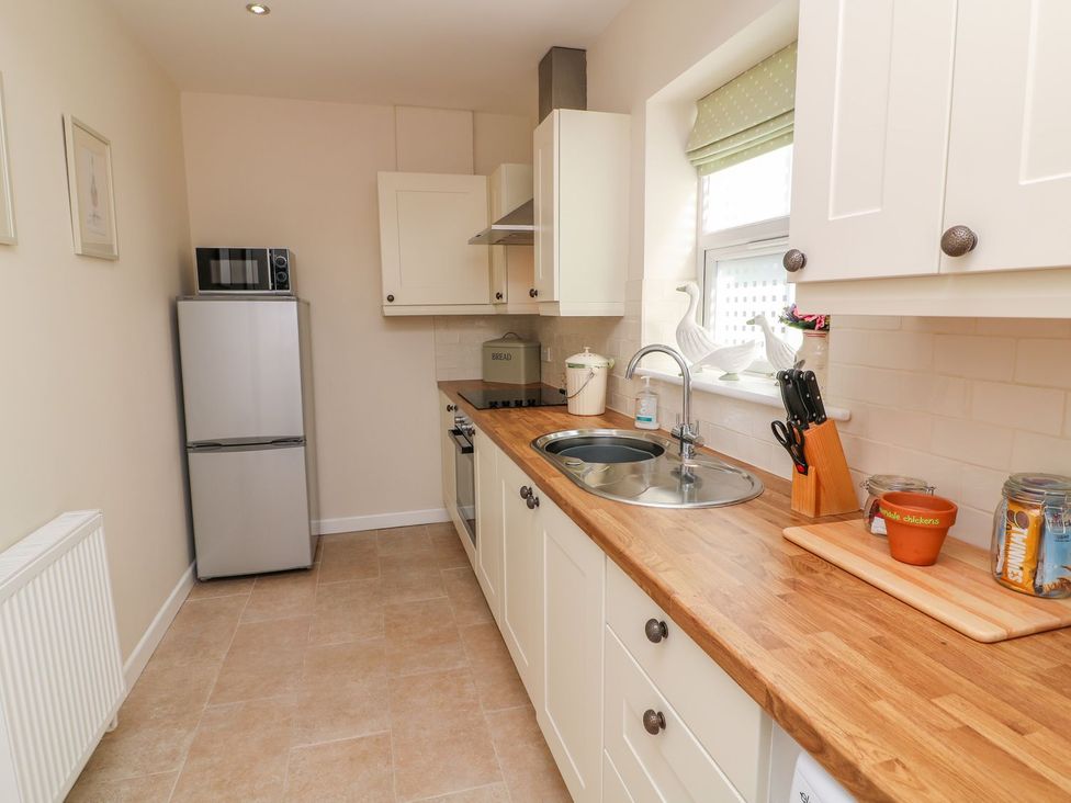 A kitchen with a refrigerator, sink, and stove at The Byre in Ashbourne