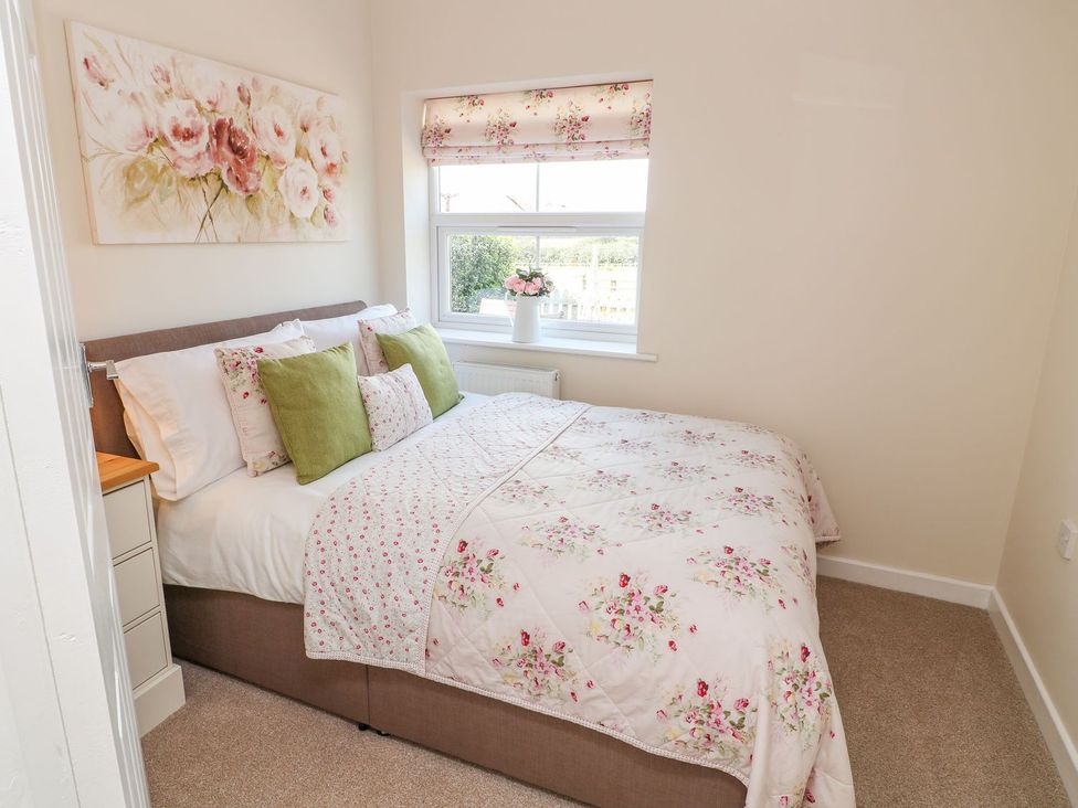 A bedroom with a bed and window at The Byre in Ashbourne