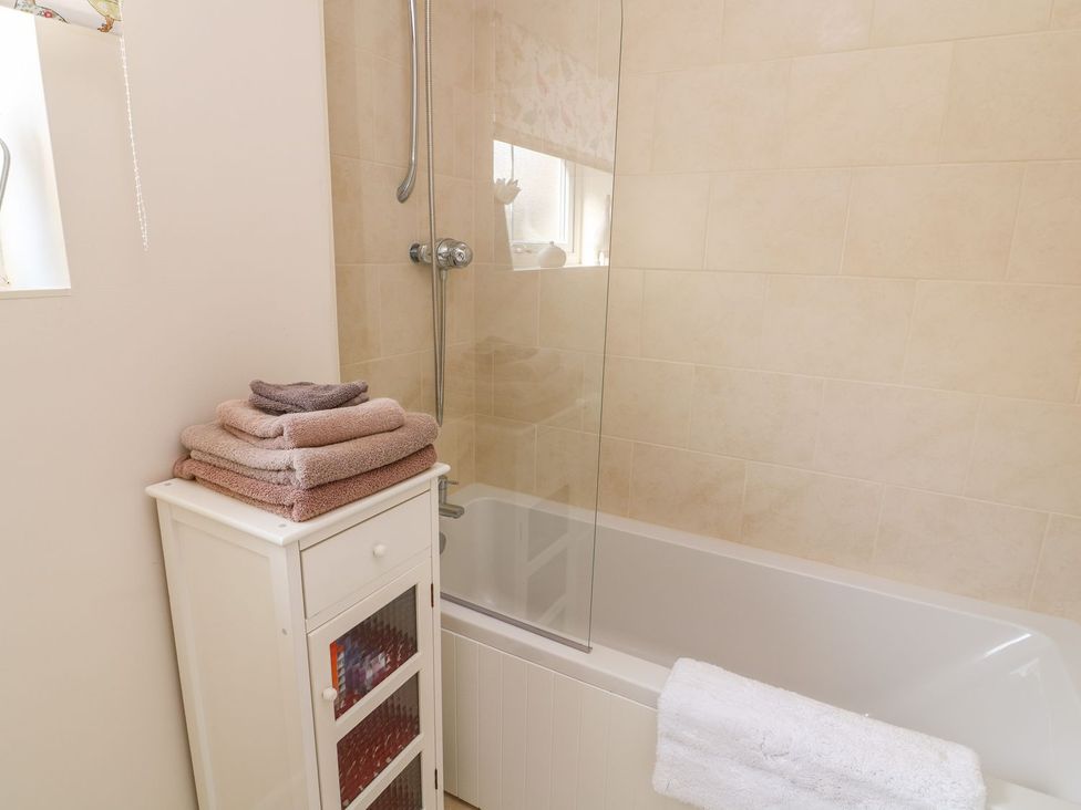 A bathroom with a bathtub and towels on a storage unit at The Byre in Ashbourne