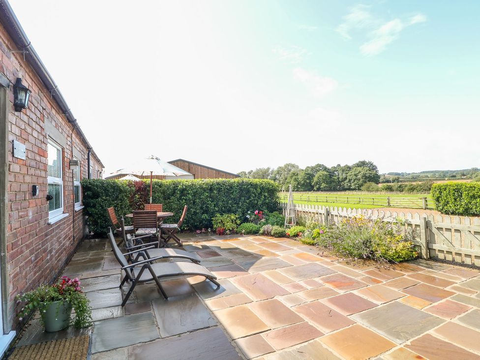 A garden with a table and chairs under an umbrella at The Byre in Ashbourne