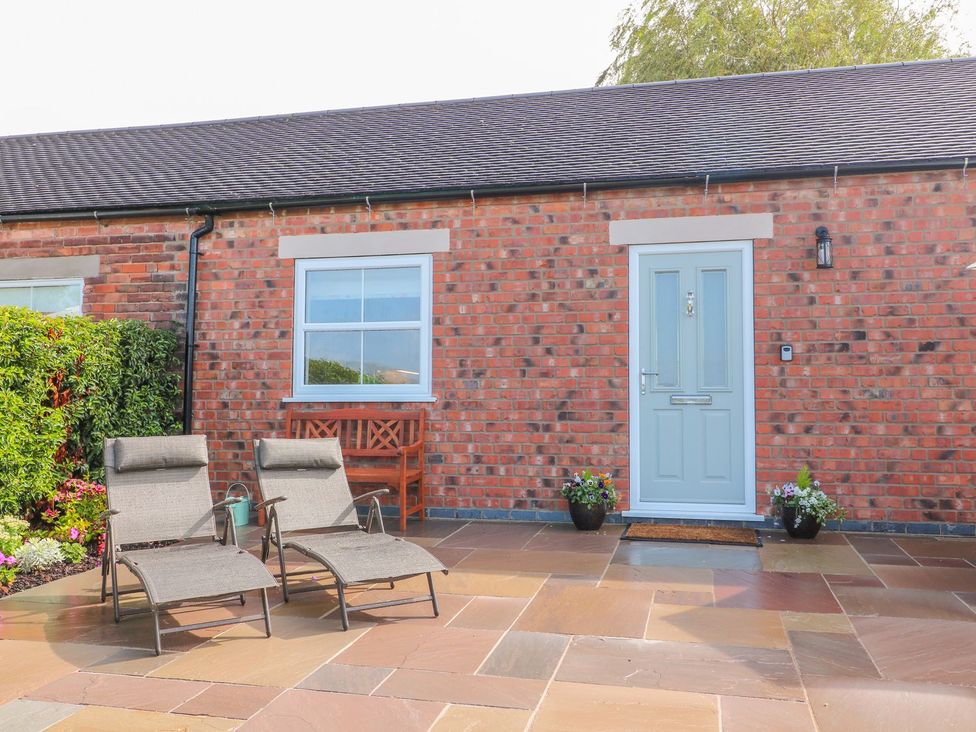 An outdoor area with loungers in front of a brick wall at The Croft in Ashbourne