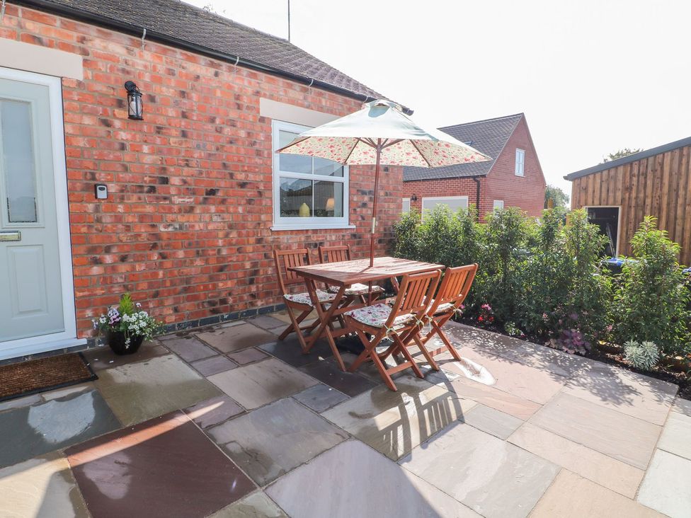 A patio with a table and chairs under an umbrella at The Croft in Ashbourne