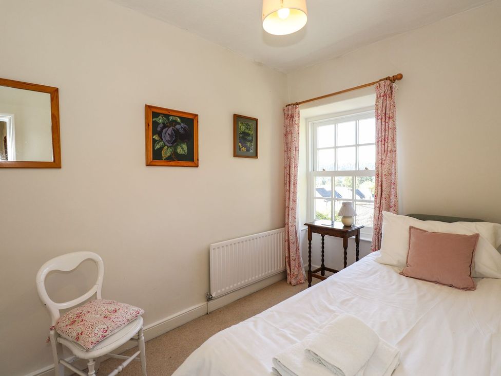 A bedroom with a bed and a chair at Jessicas Cottage in Windermere