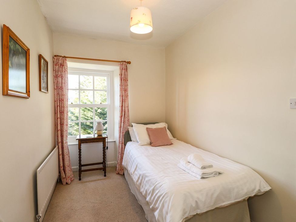 A bedroom with a bed and bedside table at Jessicas Cottage in Windermere