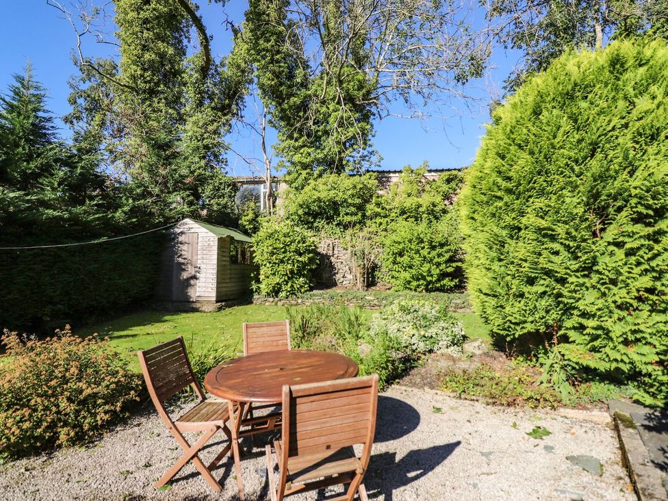 A garden with a round table and chairs along with a shed at Jessicas Cottage in Windermere