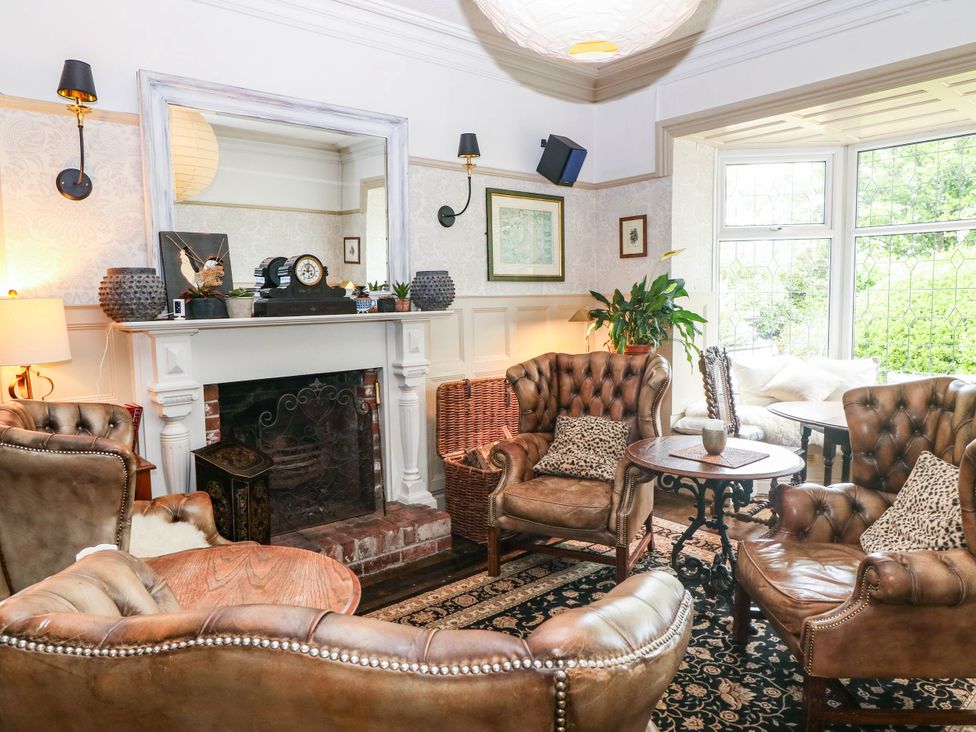 A living room with a fireplace and seating area at Meifod Country House in Caernarfon