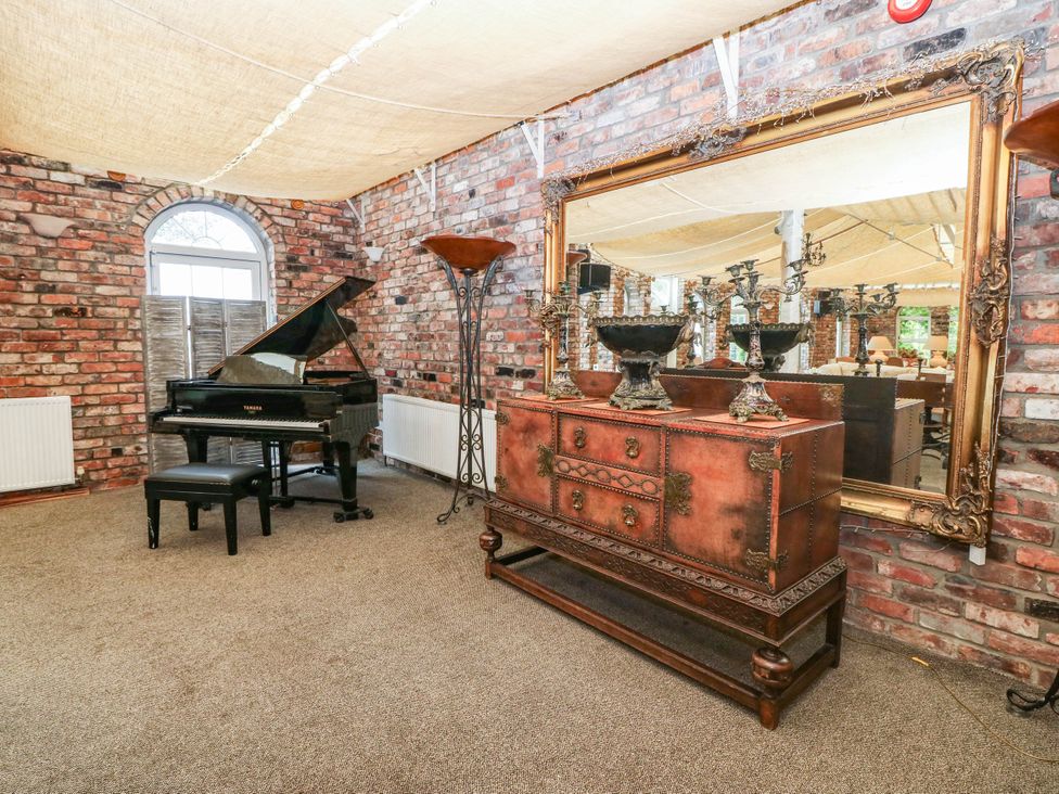 A music room with a piano and a large mirror at Meifod Country House, Caernarfon