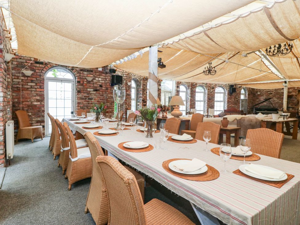 A dining room with a long table set for dinner at Meifod Country House in Caernarfon