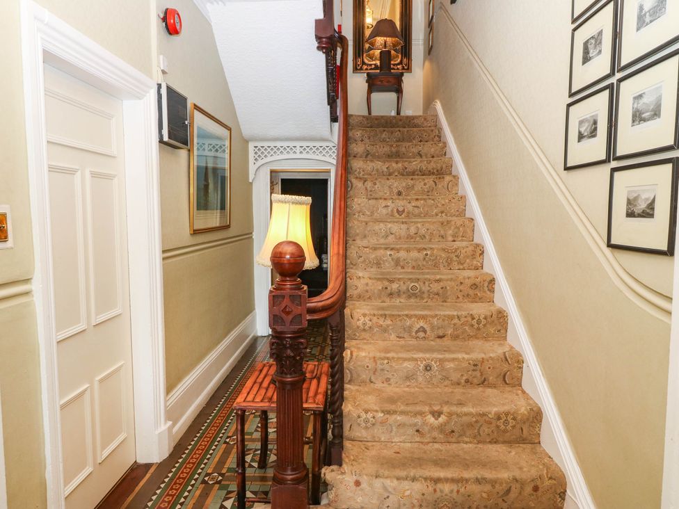 A staircase with a lamp and photo frames in a hallway at Meifod Country House Caernarfon