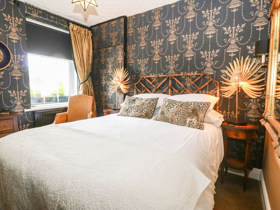 A bedroom with a bed and chair at Meifod Country House in Caernarfon