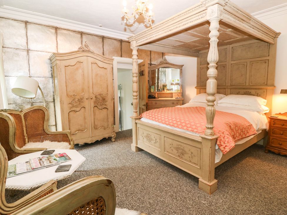 A bedroom with a canopy bed and wardrobe at Meifod Country House in Caernarfon