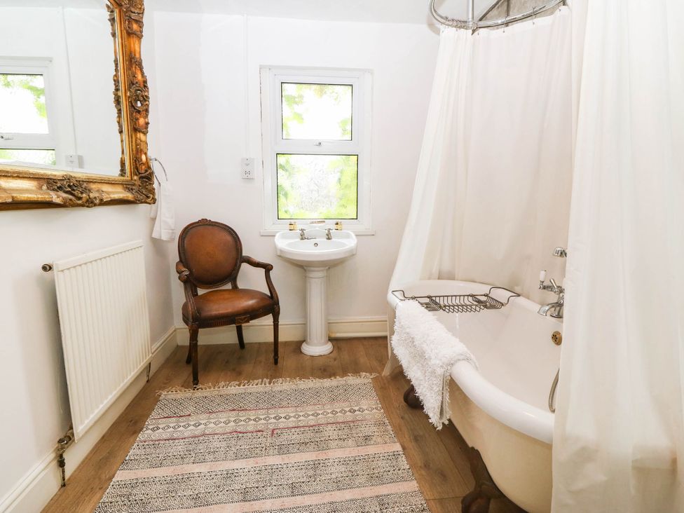 A bathroom with a bathtub and wash basin at Meifod Country House in Caernarfon
