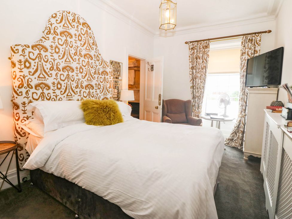 A bedroom with a bed and armchair at Meifod Country House Caernarfon